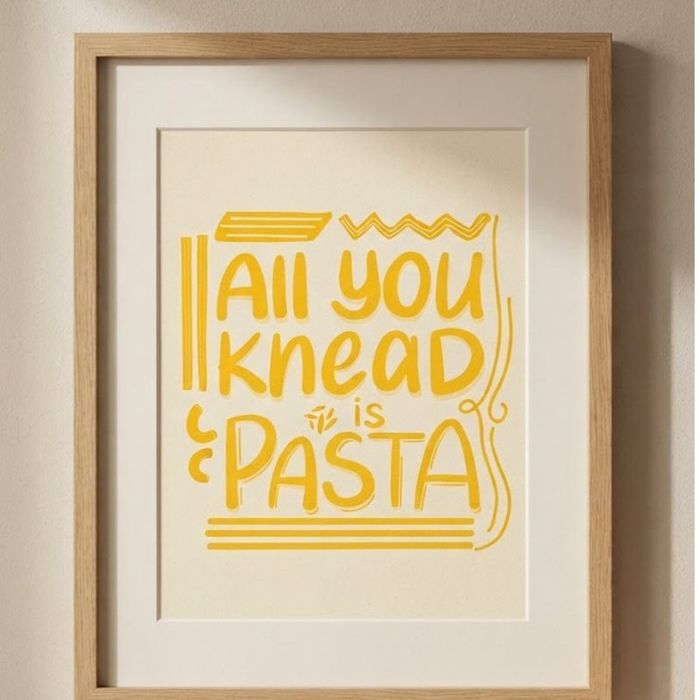A framed print of the hand-lettered 'All you knead is pasta' artwork on a wall.