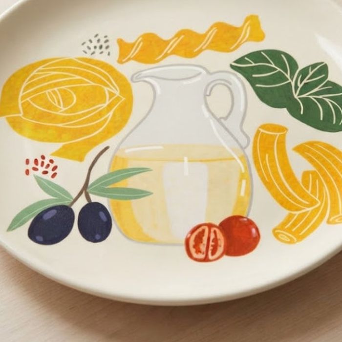 A dinner plate printed with the Pasta Love still life of an oil jug, pasta and olives.