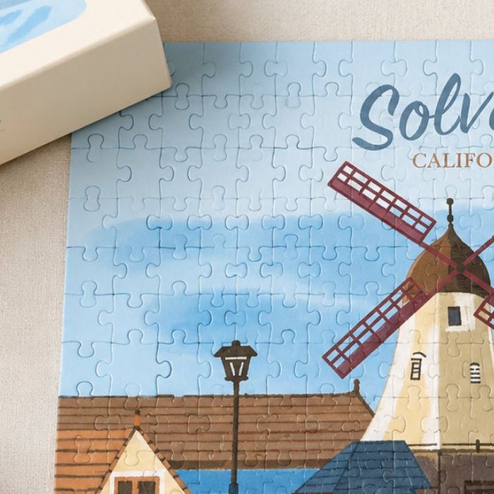 A part-completed jigsaw puzzle of the Solvang windmill illustration, beside its box.