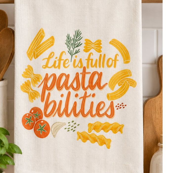 A tea towel hand-lettered 'Life is full of pastabilities', hanging in a kitchen.